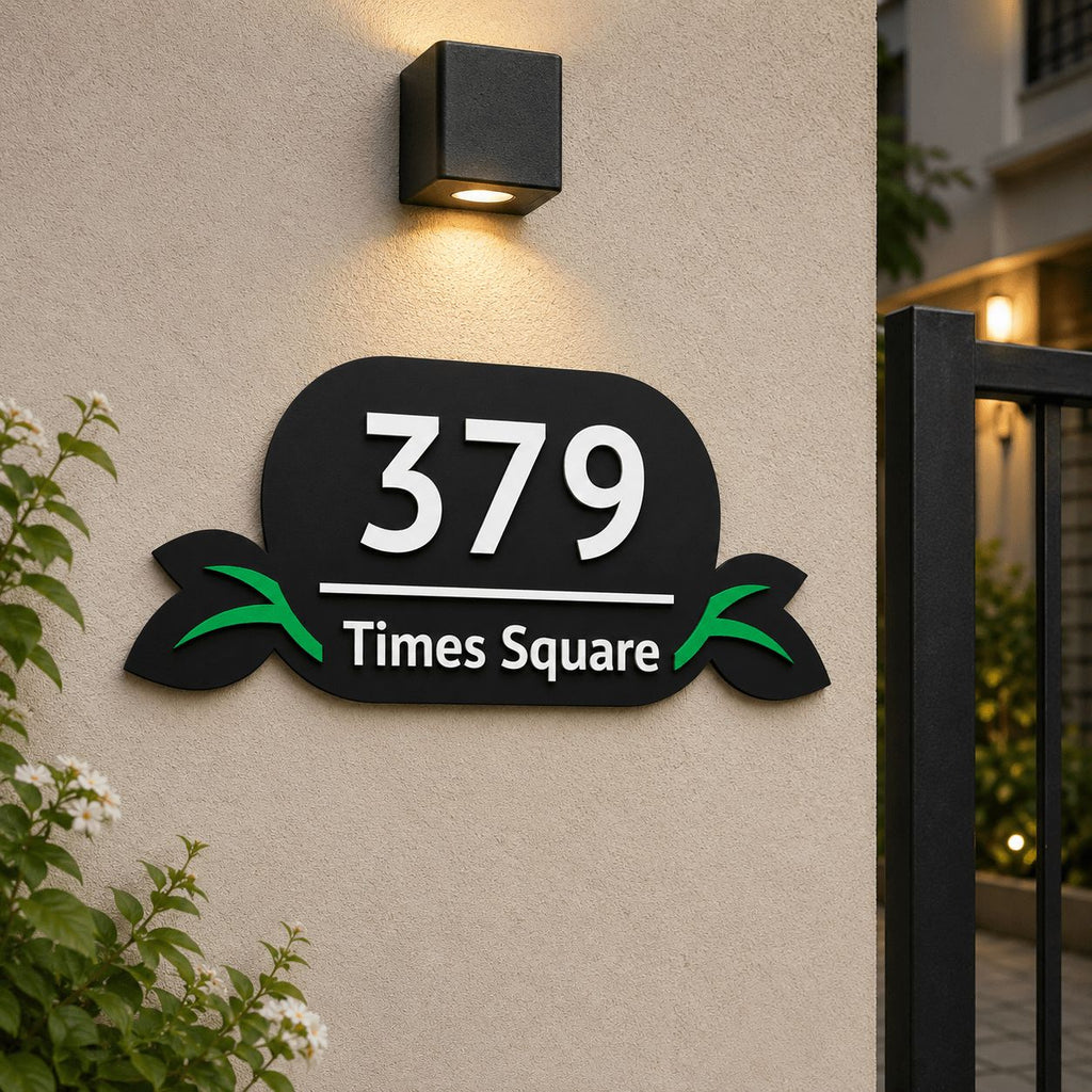 Black acrylic embossed number plate with leaf design installed on house exterior wall, India