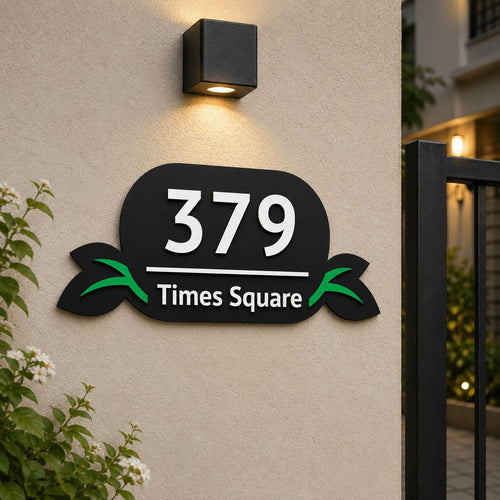 Black acrylic embossed number plate with leaf design installed on house exterior wall, India