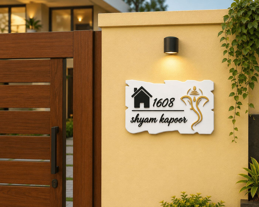 White acrylic Ganesha name plate with torn edge and gold mirror deity installed on house boundary wall, India