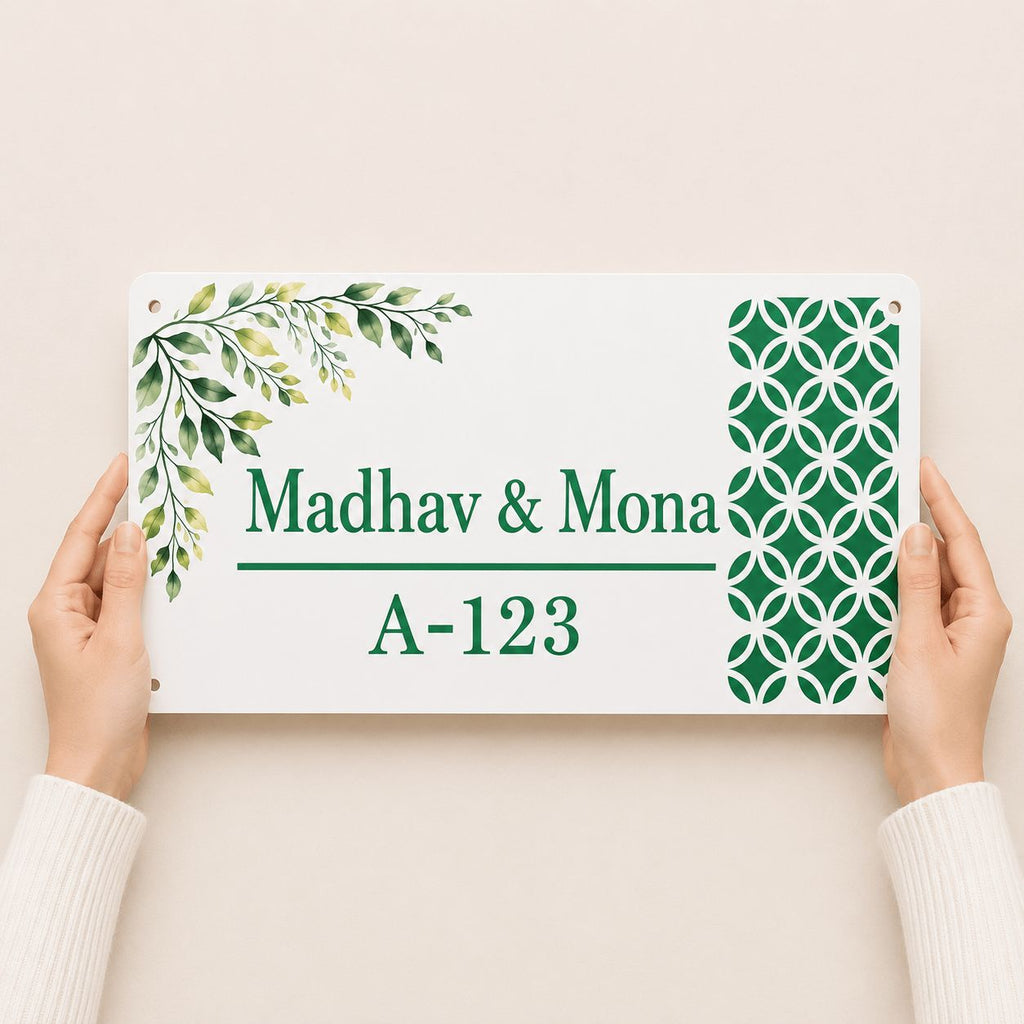 Hands holding a white acrylic couple name plate with green botanical leaf and abstract circle pattern