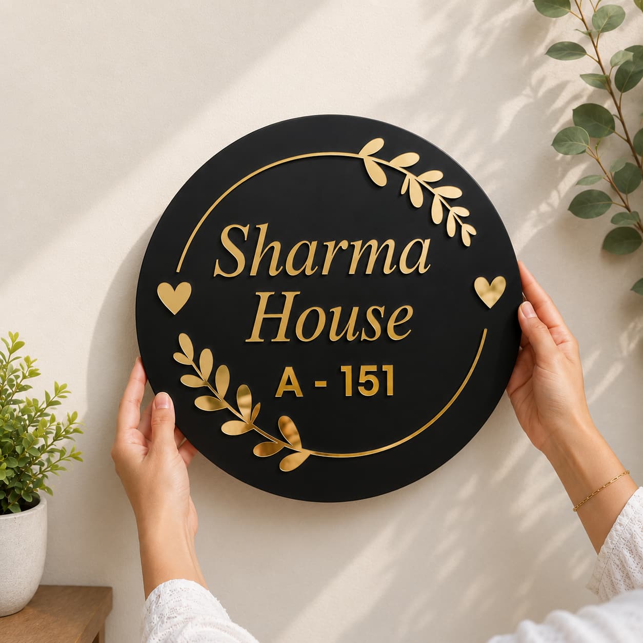 Round black acrylic house name plate installed on wall with golden mirror letters