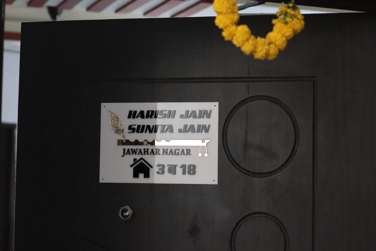 White acrylic name plate with 3mm golden mirror letters installed on a modern home entrance door for indoor and outdoor use.